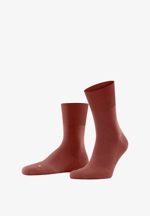 Rote Knöchelsocken aus weichem Material, mit einem gerippten Bündchen und einer glatten Textur, versehen mit einem kleinen gelben Logodetail an der Zehe.