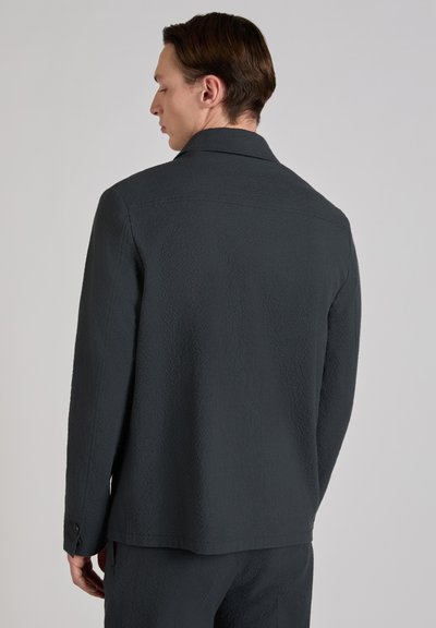 Ciemnoszara kurtka z teksturowanej tkaniny, z klasycznym kołnierzem i zapinanymi na guziki mankietami. Dopasowany krój z subtelnym wzorem.