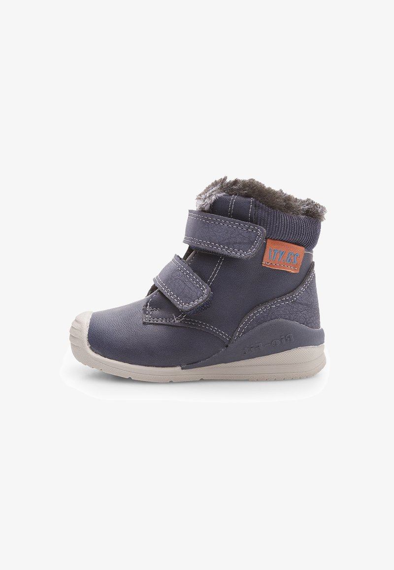 Bocanci pentru copii, de culoare bleu marin, cu două curele Velcro, guler din blană sintetică, vârf rotunjit și o talpă din cauciuc gri, embosată cu „bio-felt”.