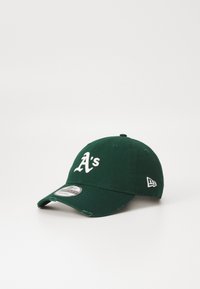 Grønn bomullslue med hvitt "A's"-logo på forsiden, buet skjerm og lite logo på siden. Har broderte detaljer og justerbar stropp.