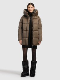 Olīvu zaļā pūdera jaka ar augstu apkakli, lielu kapuci un ķieģeļu rakstu. Valkāta pāri melnai ribotai kleitai un kombinēta ar melniem zābakiem.