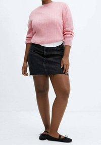 Hellrosa Strickpullover mit strukturiertem Muster, kombiniert mit einem schwarzen Jeans-Minirock mit Fransensaum und schwarzen Ballerinas.