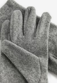 Grå fleecehandsker med fire fingre, der har en blød tekstur og rund manchet. Placeret ovenpå et matchende fleece-stykke.