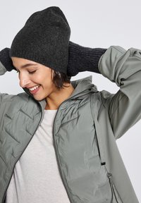 Dark gray beanie and ribbed gray gloves paired with a light gray quilted jacket. Soft textures and a fitted design are visible.