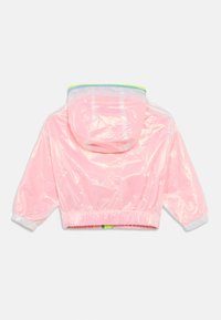 Ροζ διαφανές κοντό μπουφάν με κουκούλα, ελαστικά μανίκια και ζώνη στη μέση. Διαθέτει πράσινη λεπτομέρεια γύρω από το άνοιγμα της κουκούλας. Υφή επιφάνειας με ριζώματα.