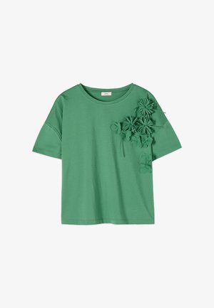 Camicia verde a maniche corte con scollo rotondo, caratterizzata da applicazioni floreali in rilievo raggruppate nella parte superiore sinistra del petto e nella zona della spalla.