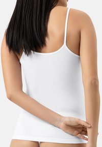 Top in cotone bianco senza maniche con spalline sottili, caratterizzato da una vestibilità attillata e una texture liscia. Il retro presenta cuciture minime e un collo rotondo.