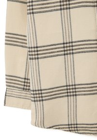 Beige flanellen stof met een zwart en bruin schotse ruitpatroon. Heeft een zachte textuur en een omgezoomde rand. Geschikt voor casual draag.