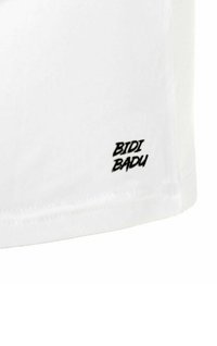 Camiseta blanca con el logo negro "BIDI BADU" impreso en la parte inferior izquierda. Fabricada en suave tejido de algodón con un corte regular.