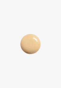 Beige cream texture in a circular shape with a glossy finish against a white background.