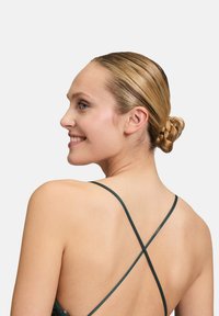 Ärmelloses Kleid mit einem tiefen Rückenausschnitt, ausgestattet mit dunkelgrünen Spaghettiträgern, die sich überkreuzen. Glatter Stoff mit taillierter Silhouette.