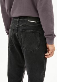 Zwarte denim jeans met een slanke pasvorm, voorzien van achterzakken, een leren patch met logo en een textuurafwerking van de stof.