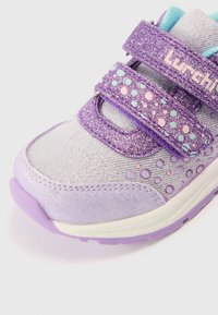 Παντόφλα σε μωβ και γκρι χρώμα με λαμπερά στοιχεία, δύο ιμάντες βέλκρο και σχέδια με πουά. Διαθέτει υφή επιφάνειας και ελαφρύ πάτο.