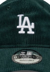 Een donkergroene corduroy honkbalpet met een witte geborduurde "LA"-logo, verstelbare band en een New Era-label.