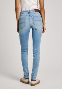 Ljusblå slim jeans med en blekt finish, med hög midja, två bakfickor och en brun läderlapp vid midjan.