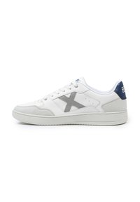Baskets blanches avec un logo gris, des accents en daim, une tige en cuir lisse, un bout rond, une semelle plate et un patin de talon bleu contrasté.