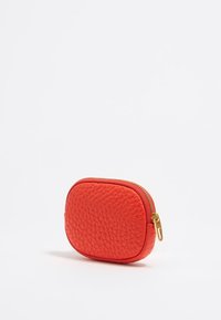 Bolsa de cuero rojo texturizado con forma redondeada, con un cierre de cremallera dorado y bordes acabados. Diseño compacto y portátil para accesorios.