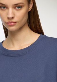 Felpa in cotone blu con collo rotondo e rifiniture a costine, caratterizzata da una texture liscia e una vestibilità rilassata. Senza motivi o dettagli aggiuntivi.