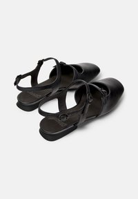 Schwarze Slingback-Schuhe mit runder Zehenpartie, ausgestattet mit einer dekorativen Schnalle und einem niedrigen Absatz, aus einer Draufsicht präsentiert.