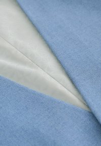 Tissu bleu plié révélant une doublure blanche lisse avec un motif étoile géométrique subtil en dessous.