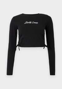 Black long-sleeve cropped top featuring gathered side detailing, adjustable ties, and white "Santa Cruz" embroidery on the front.