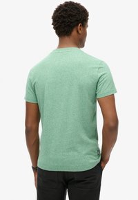Green heathered short-sleeve t-shirt, crew neck design, soft texture, with a small label at the hem and a straight cut for a relaxed fit.