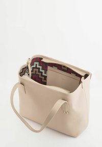 Bolso tote de cuero beige con acabado texturizado, que cuenta con un forro colorido con estampado. Incluye un bolsillo interior y detalles en hardware dorado.