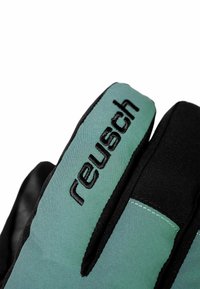 Grüne und schwarze Handschuhe mit einer weichen Außenseite, die das "reusch"-Logo in Schwarz tragen. Das Design umfasst kontrastierende Texturen und Nähte.