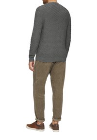Grau gestrickter Pullover mit Rautenmuster, kombiniert mit sandfarbenen Cordhosen und braunen Sneakers. Lässiger Schnitt mit hochgekrempelten Hosenöffnungen.