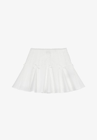 Jupe évasée blanche avec une finition texturée, présentant une taille en dentelle et de petits nœuds sur l'ourlet, créant un design ludique.