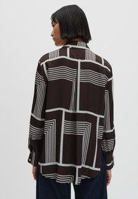 Camicia a maniche lunghe, con bottoni, in tessuto marrone con strisce geometriche bianche. Caratterizzata da una vestibilità rilassata e maniche con polsini. Vista posteriore.