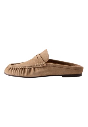 Mule en daim marron clair à enfiler avec couture mocassin et semelle plate noire, vue de côté.