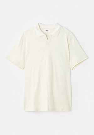 Polo shirt de culoare crem, cu guler clasic, mâneci scurte și o ușoară deschidere în formă de V la gât. Textură netedă și design minim.