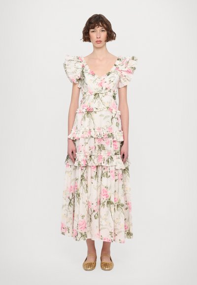 Witte maxi-jurk met bloemenprint en roze rozen, met volants mouwen en gelaagde ontwerpen. Gecombineerd met gouden gevlochten ballerina's. Soepele, lichte stof.
