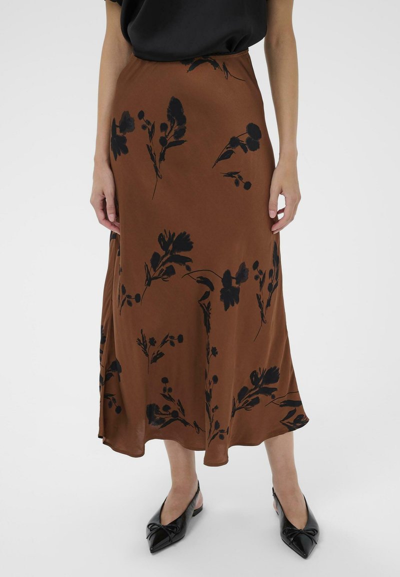 Jupe midi en tissu léger à motif floral marron, avec des imprimés de fleurs noirs. Assortie avec des chaussures noires à bouts pointus.
