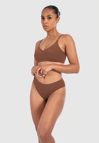 Braunes Dessous-Set mit nahtlosem Bralette mit verstellbaren Trägern und hochgeschnittenem Bikini-Slip. Glatter Stoff und minimalistisches Design.