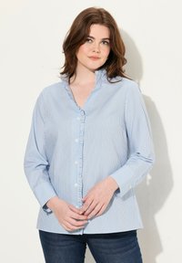 Camicia button-up di colore azzurro chiaro con righe verticali bianche, dotata di colletto alto, maniche lunghe e una vestibilità comoda. Materiale in cotone.