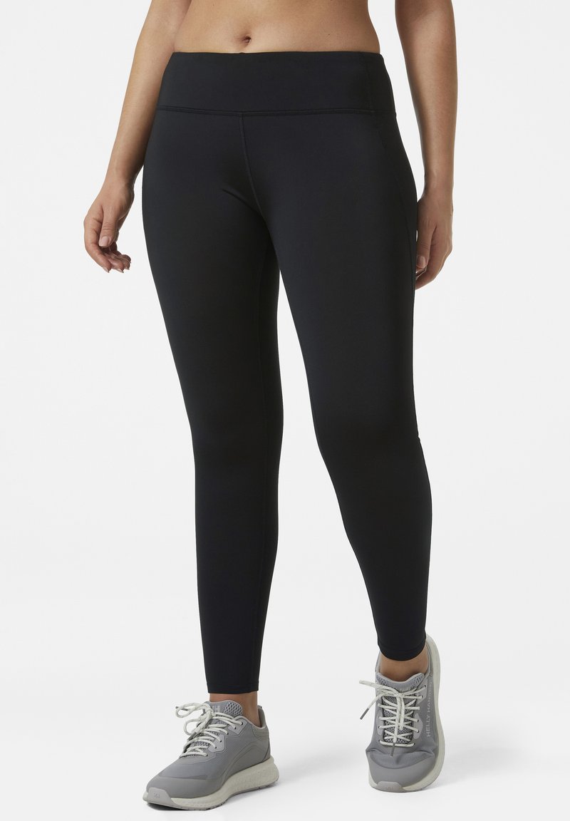 Zwarte legging met een hoge tailleband, gemaakt van rekbare stof. Gladde textuur en aansluitend ontwerp, gecombineerd met grijze sportschoenen.