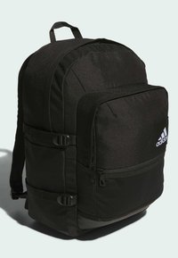 Zaino nero con tessuto testurizzato, molteplici scomparti con zip, spallacci regolabili e base in plastica. Presenta un logo Adidas.