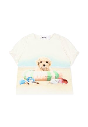 Camiseta blanca de manga corta con un cachorro dentro de un aro inflable verde y rosa sobre la arena, rodeado de coloridas conchas marinas.