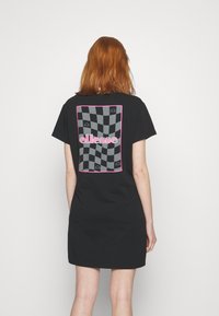 Robe t-shirt noire avec un motif à damiers et des accents roses ; présente un logo graphique au dos dans un cadre contrastant.