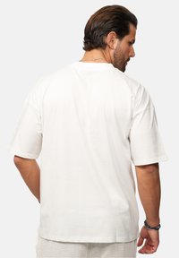 Weißes Baumwoll-T-Shirt mit lässiger Passform, kurzen Ärmeln und Rundhalsausschnitt. Hat einen schlichten Rücken ohne zusätzliche Designelemente.
