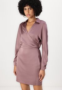 Robe portefeuille en satin mauve doux, avec un col, des manches longues et une taille cintrée. Texture lisse avec un minimum de détails.