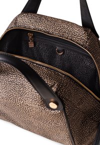 Bolso negro y beige con un patrón texturizado, cuenta con un cierre superior de cremallera, un bolsillo interior con cremallera y detalles de hardware en tono dorado.