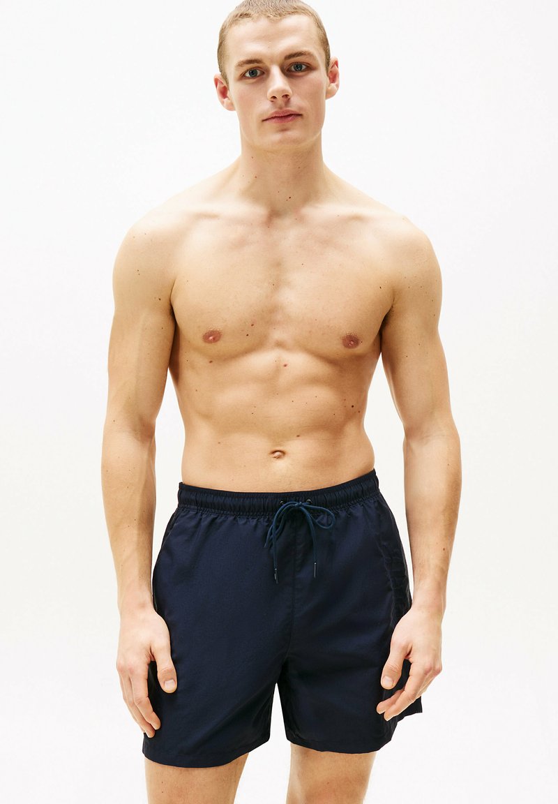Marineblaue Schwimmshorts mit einem Kordelzugbund und einer glatten Textur, die ein einfaches, schmuckloses Design aufweisen.