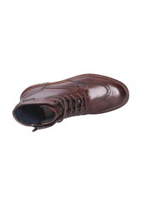 Bruine leren enkelboot met decoratieve stiksels, gestructureerde kraag, vetersluiting en een contrasterende binnenvoering. Heeft een ronde neus.
