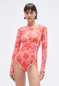 Plavky s dlouhými rukávy v živé červené barvě s květinovým potiskem v růžové a bílé, s kontrastním bílým prošitím a přiléhavým střihem.