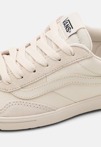 Beige Leder-Sneaker mit strukturierten Wildleder-Details, Baumwollsenkeln und einem gestickten Design. Mit Vans-Branding auf der Zunge.