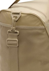 Beige sporttas met een mesh-paneel, kunststof hardware en een stevige schouderband. De textuur is glad met een gestructureerde, rechthoekige vorm.