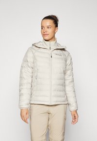 Lett pufferjakke i myk beige med horisontal quilt, full glidelås, påsydde hette og to glidelåslommer på sidene.